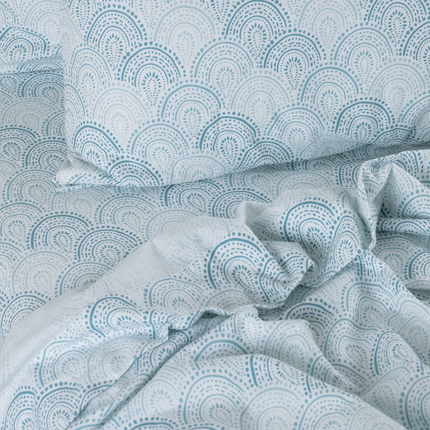 Teal and white patterned bedding set on a bed.