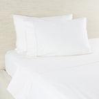 White bed sheets and pillows on a bed with a beige headboard.