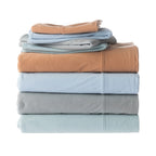 Stack of folded bed sheets in brown, blue, and gray on a white background