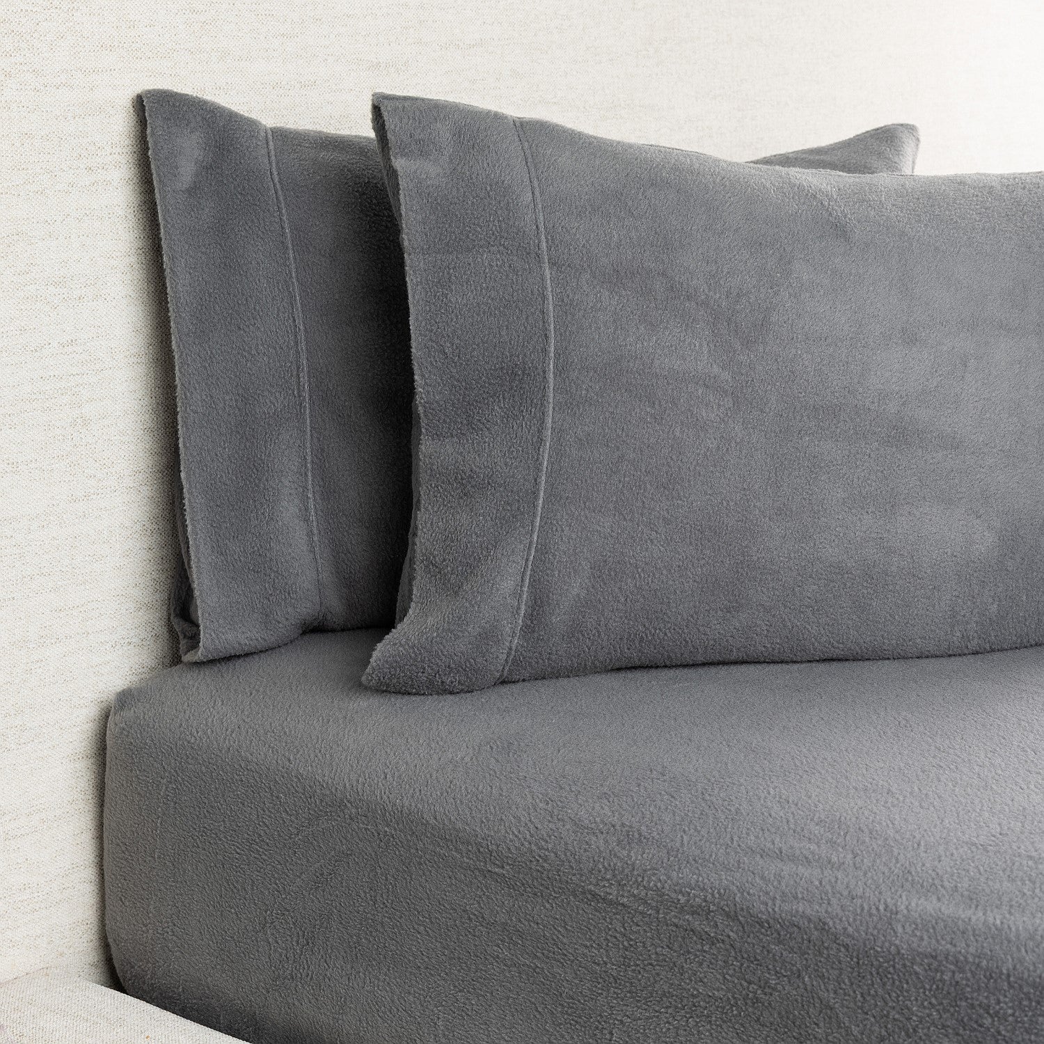 Gray bedding set with pillows on a bed against a light background