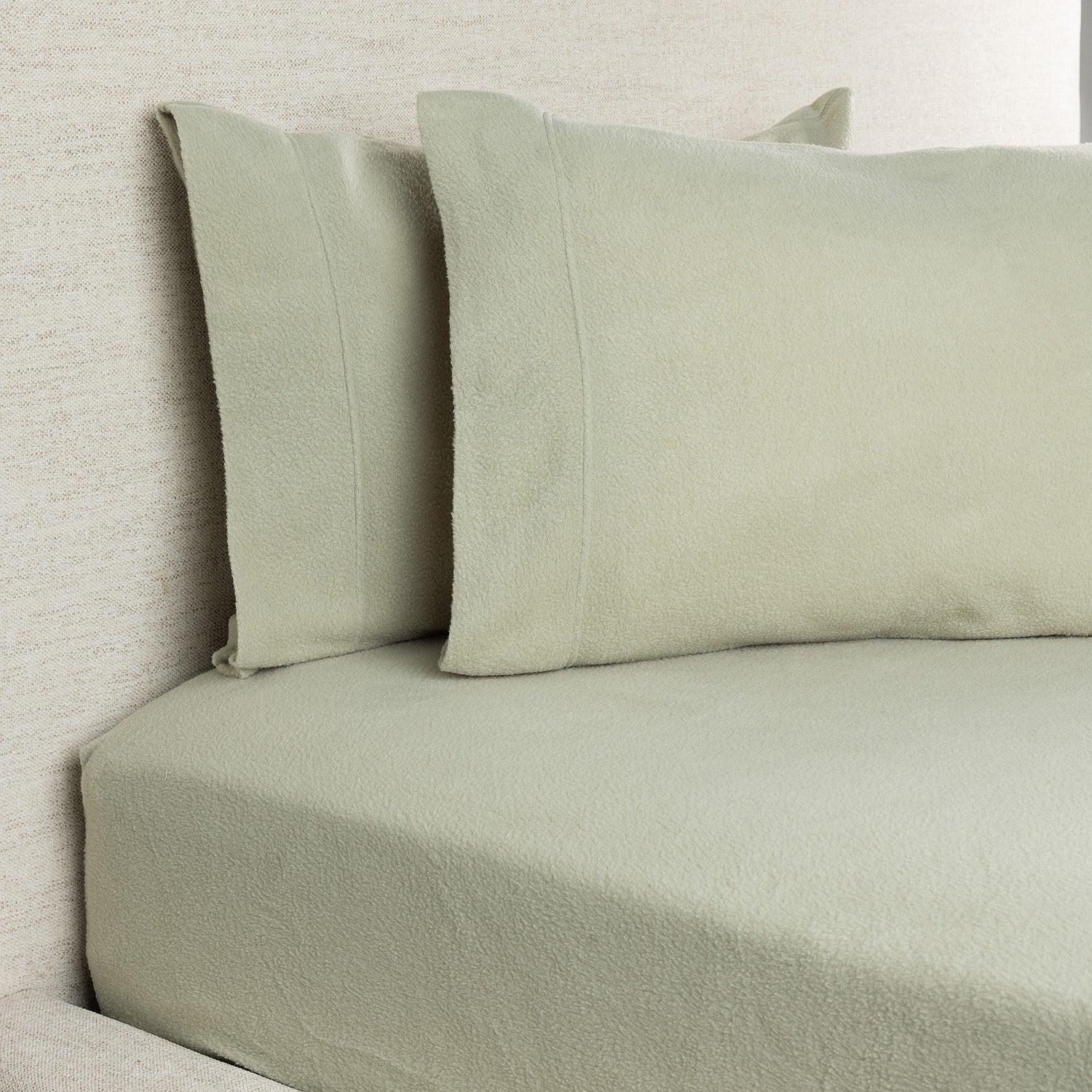Light green bedding set on a bed with a neutral background