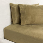 Brown bed sheets and pillows on a bed against a white wall