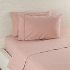 Pink bed sheets and pillowcases on a bed with a neutral background