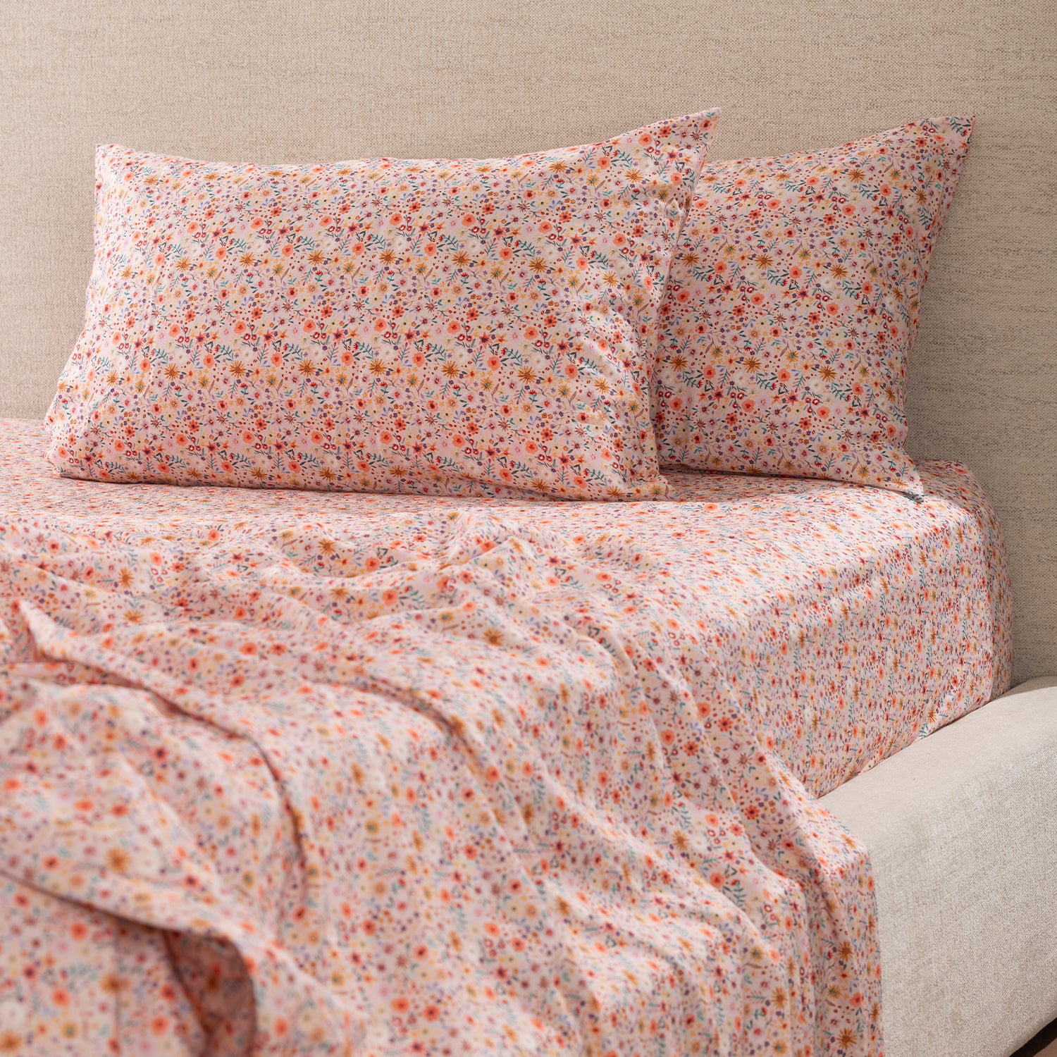 Marlo Mia Floral Flat Sheet styled on a bed with matching floral pillowcases, featuring a delicate all-over floral print in soft pink, coral, yellow and blue tones.