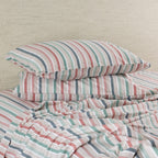 Striped bedding set with pillows on a bed against a beige wall.