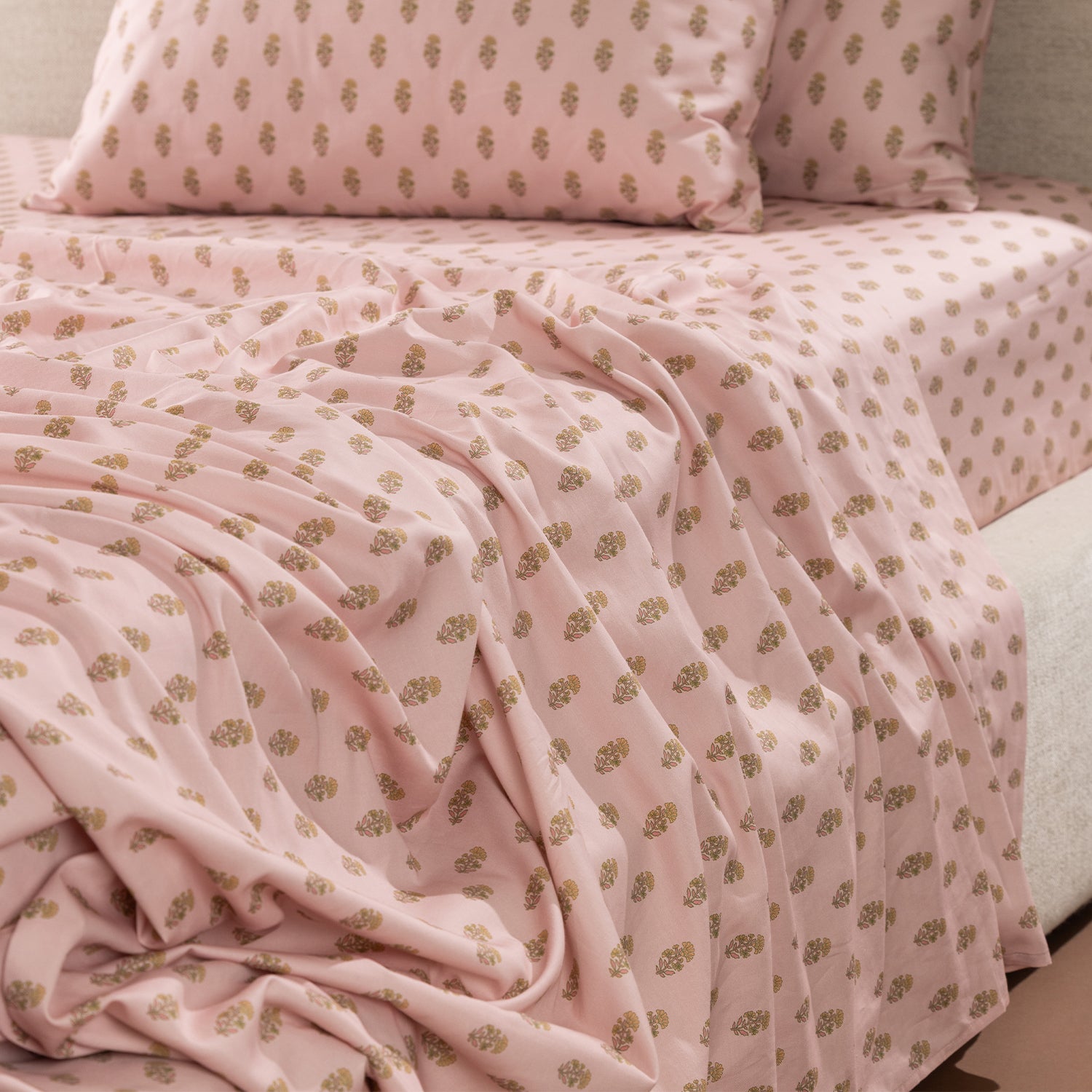Close-up of the Marlo Mia Flat Sheet draped across a bed, showcasing the soft pink colour and repeating floral motif design.