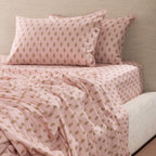 Marlo Mia Flat Sheet in soft pink with a repeating floral motif, styled on a bed with matching pillowcases and fitted sheet.