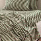 Close-up of the Marlo Mia Stripe Flat Sheet styled on a bed, showcasing the pink and green striped pattern and soft cotton sateen finish.