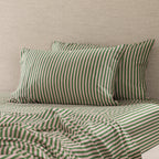 Two Marlo Mia green and blush stripe pillowcases styled on a bed with matching striped fitted sheet and coordinating bedding.